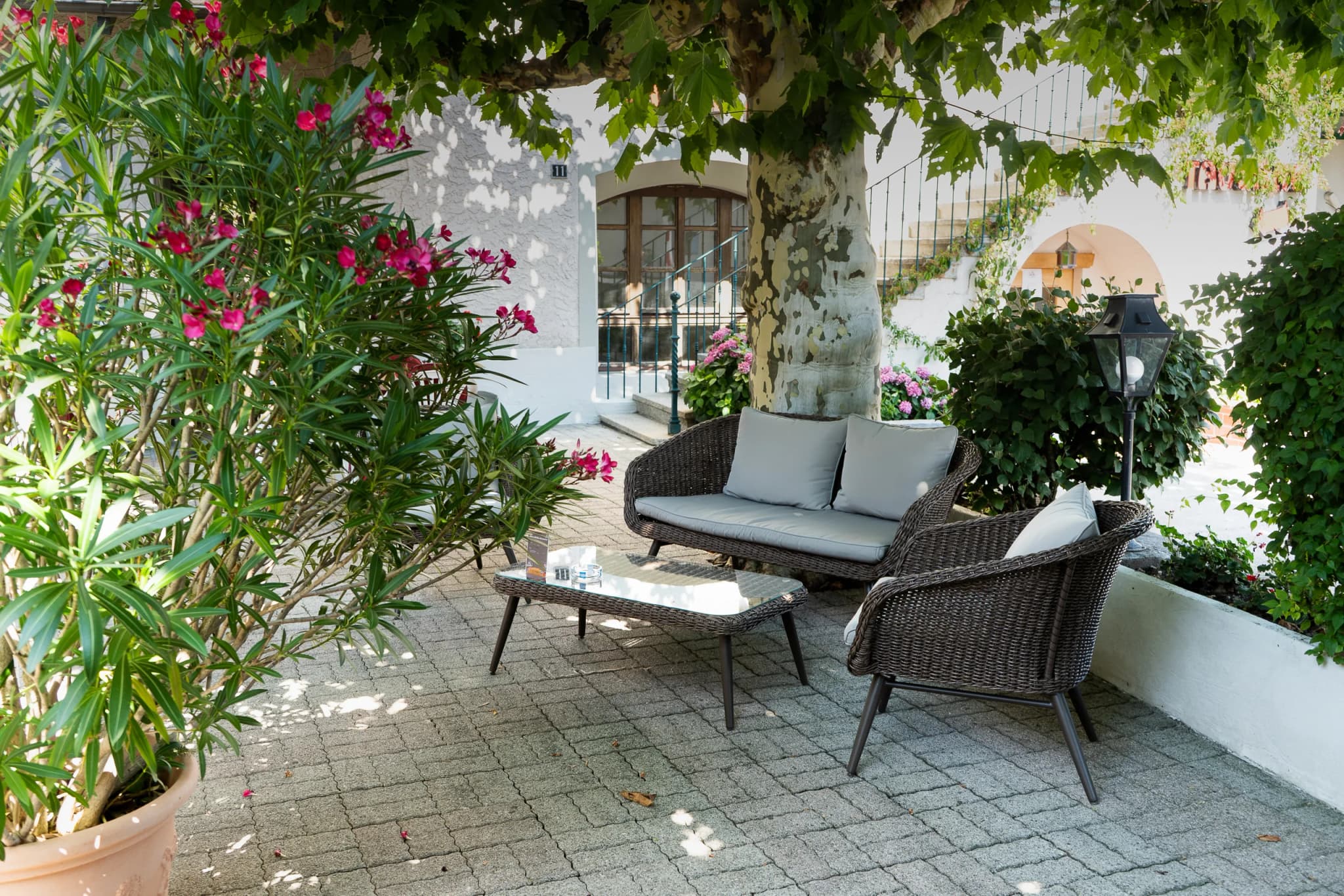 Salon de jardin en rotin à l’ombre d’un platane, sur la terrasse de l’Hôtel de Bahyse